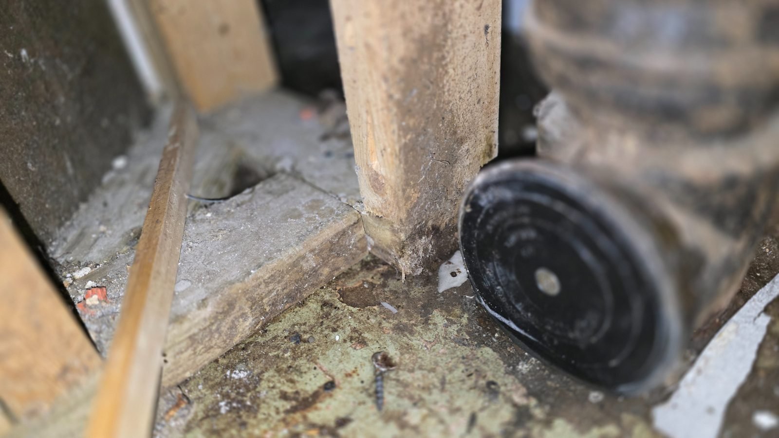 Exposed framing and damaged material beside a pipe